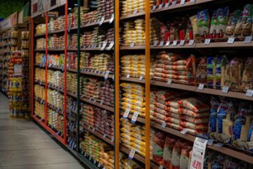 A grocery store aisle filled with various rice and grain packages neatly organized on shelves.