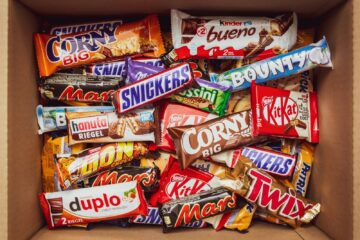 A cardboard box filled with a variety of assorted chocolate candy bars